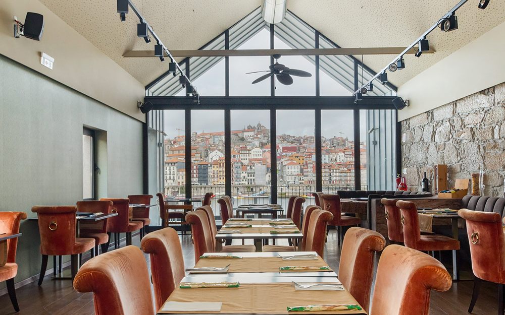 Sala do S. Martino Prestige com cadeiras de couro e janela envidraçada sobre o Douro e o Porto