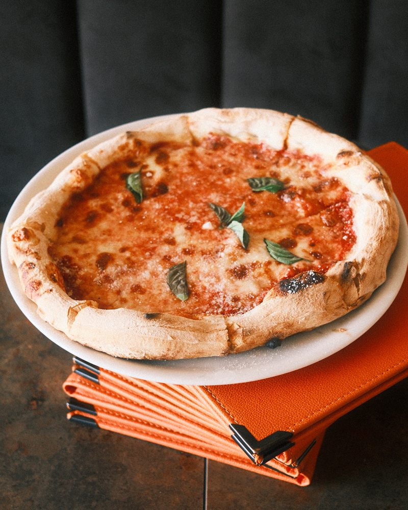 Pizza napoletana com manjericão fresco, pousada sobre ementas cor de laranja